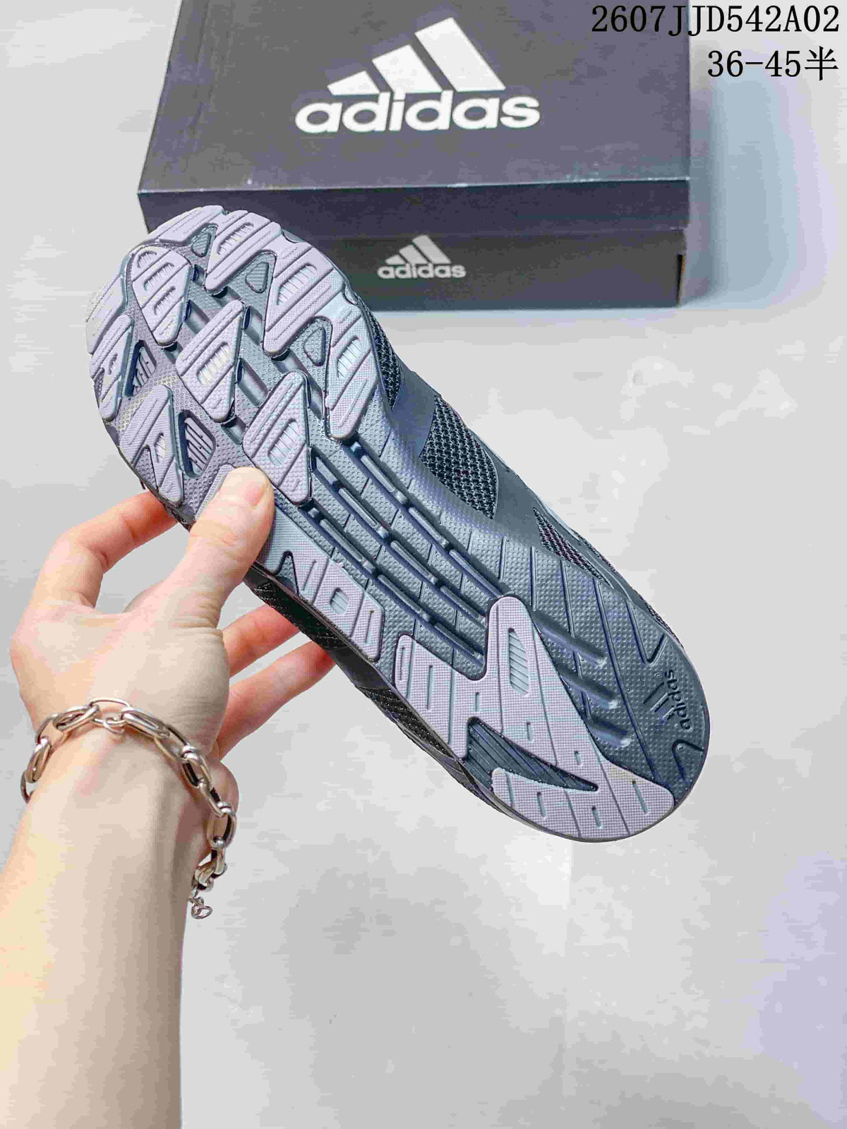 Close-up of the patterned outsole on a charcoal gray Adidas sneaker
