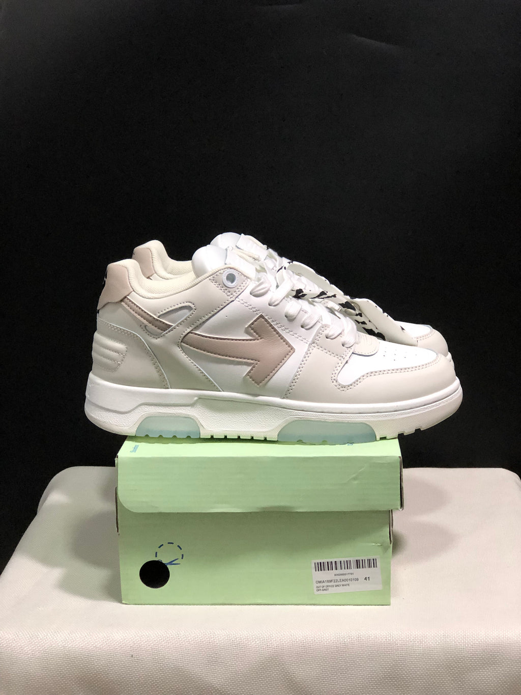 Side view of the white low-top sneakers showing layered panels, arrow graphics, padded collars, and translucent outsole sections.