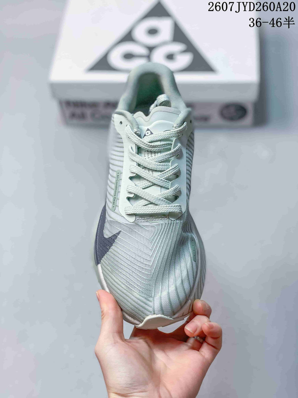 Top view of the sneaker showing the pale green textured upper, navy side logo, laces, and tongue branding.