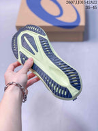 Close view of the patterned outsole on a navy and lime running shoe, with an ASICS shoebox in the background.