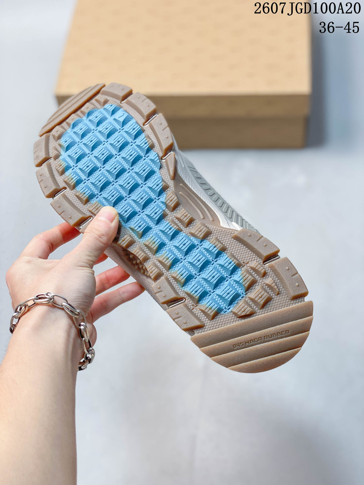 Close view of the sneaker outsole showing a rugged tan rubber-colored perimeter and contrasting blue patterned traction area.