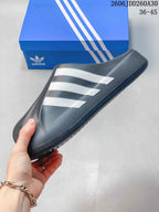 Side profile of a charcoal closed-toe mule slide with three white stripes