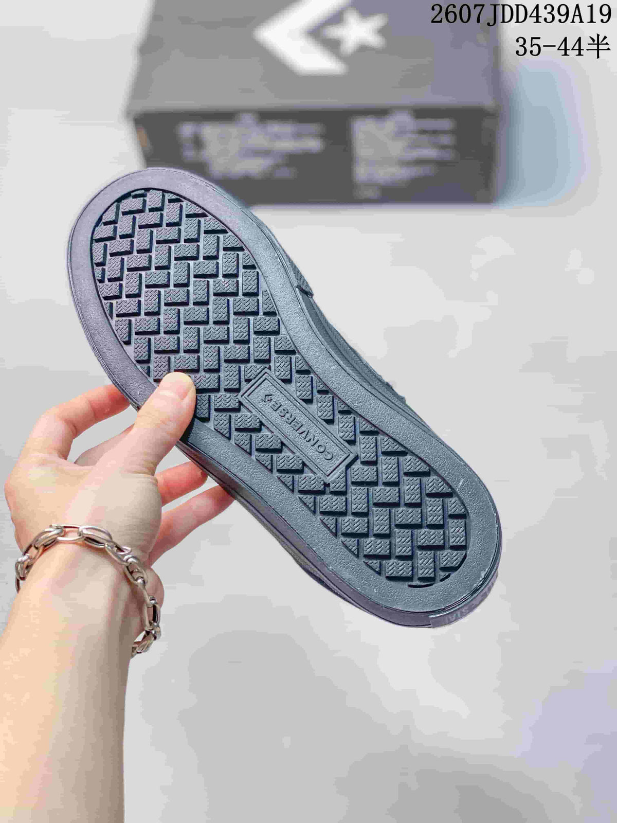 Close-up of the textured rubber outsole with Converse branding on a black low-top sneaker; style code and size range text appear above.