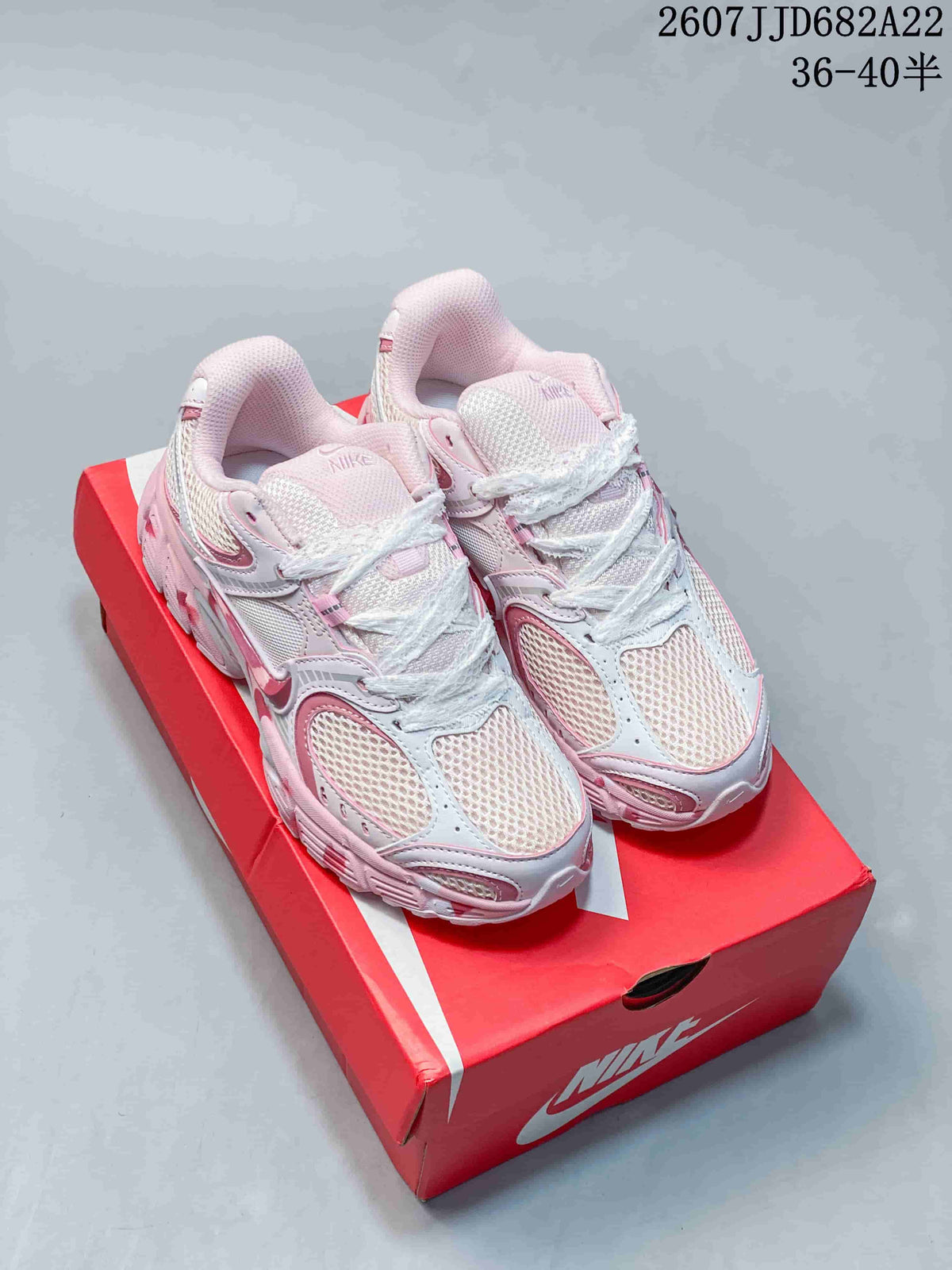 Pair of white and pink Nike V5 RNR sneakers displayed on a red shoebox.