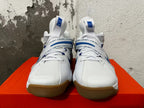 Front view of white Nike basketball shoes with blue accents, laces, and midfoot straps.