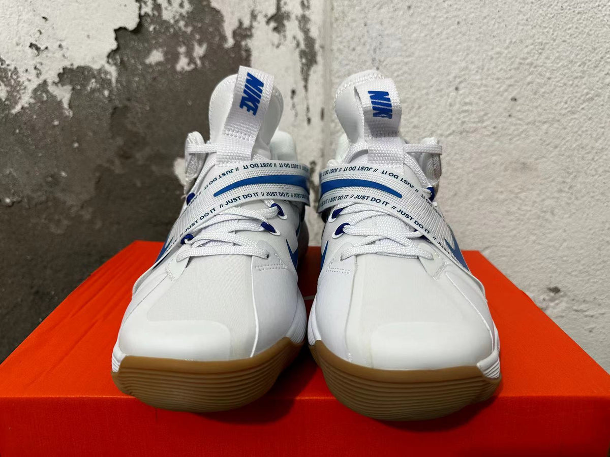 Front view of white Nike basketball shoes with blue accents, laces, and midfoot straps.