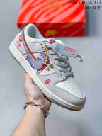 Light grey and white low-top sneaker with red trim, horse artwork and a hanging decorative charm.