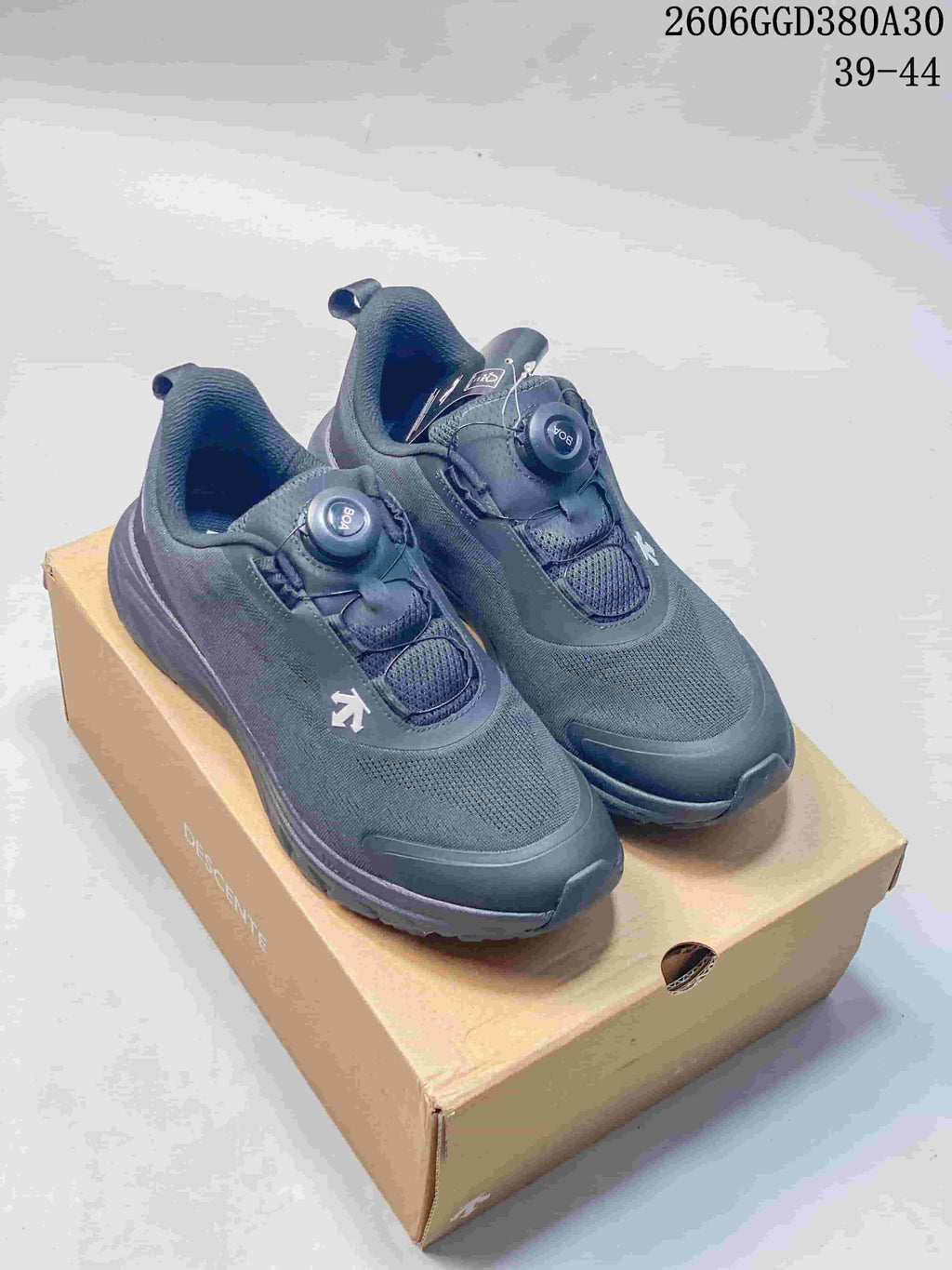Pair of dark gray Descente Fitstep Wire shoes with dial closures, shown on a shoe box