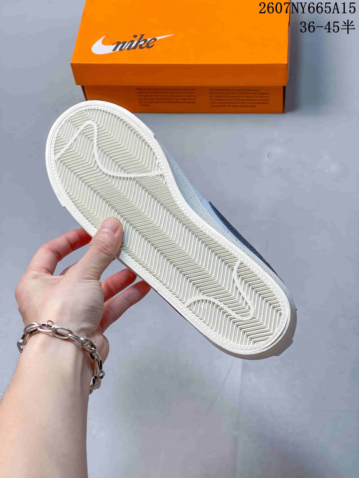 Close-up of the textured herringbone-style rubber outsole with an orange shoebox in the background.
