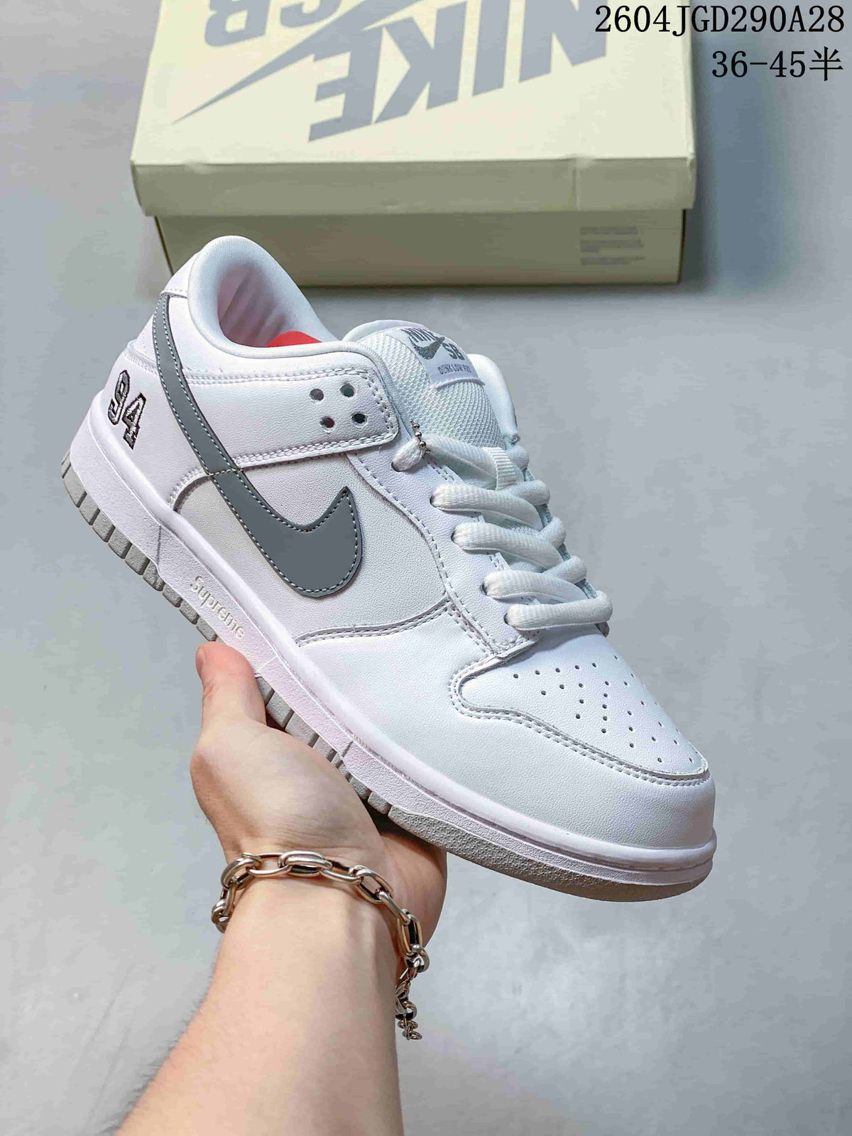 White Nike Dunk Low sneaker with gray accents and Swoosh; image overlay shows sizes 36–45.5.