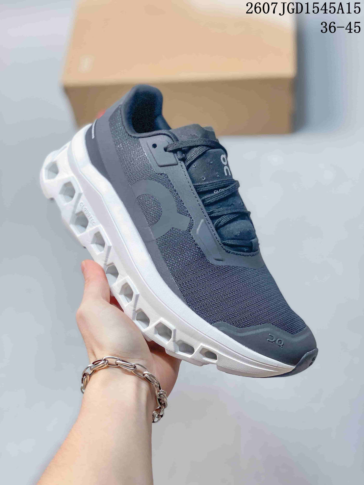 Angled side view of the dark gray sneaker with its white geometric outsole and layered upper panels.