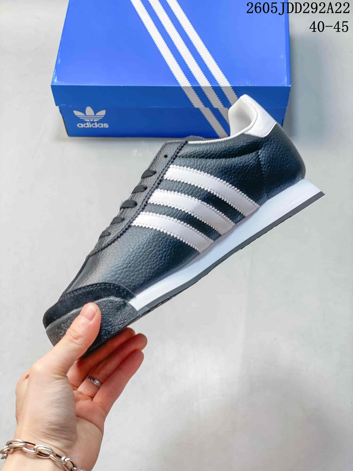 Side view of a dark gray adidas Samoa sneaker with white three-stripe details and a low white midsole.