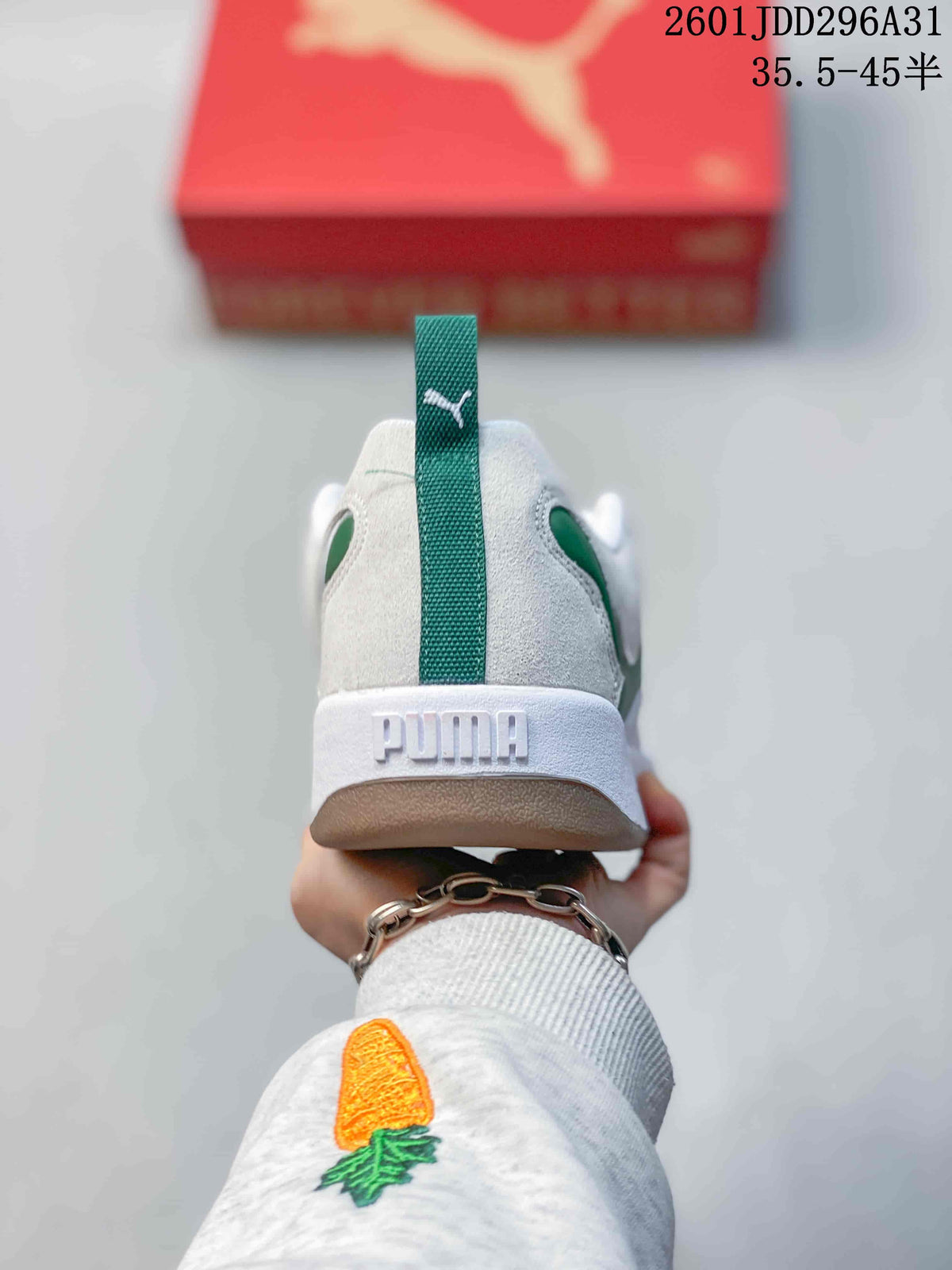 Rear view of a white PUMA sneaker with a green heel pull tab, PUMA heel branding and a brown-toned outsole.
