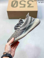 Side profile showing the grey upper, orange stripe detail, laces, and ribbed translucent outsole.