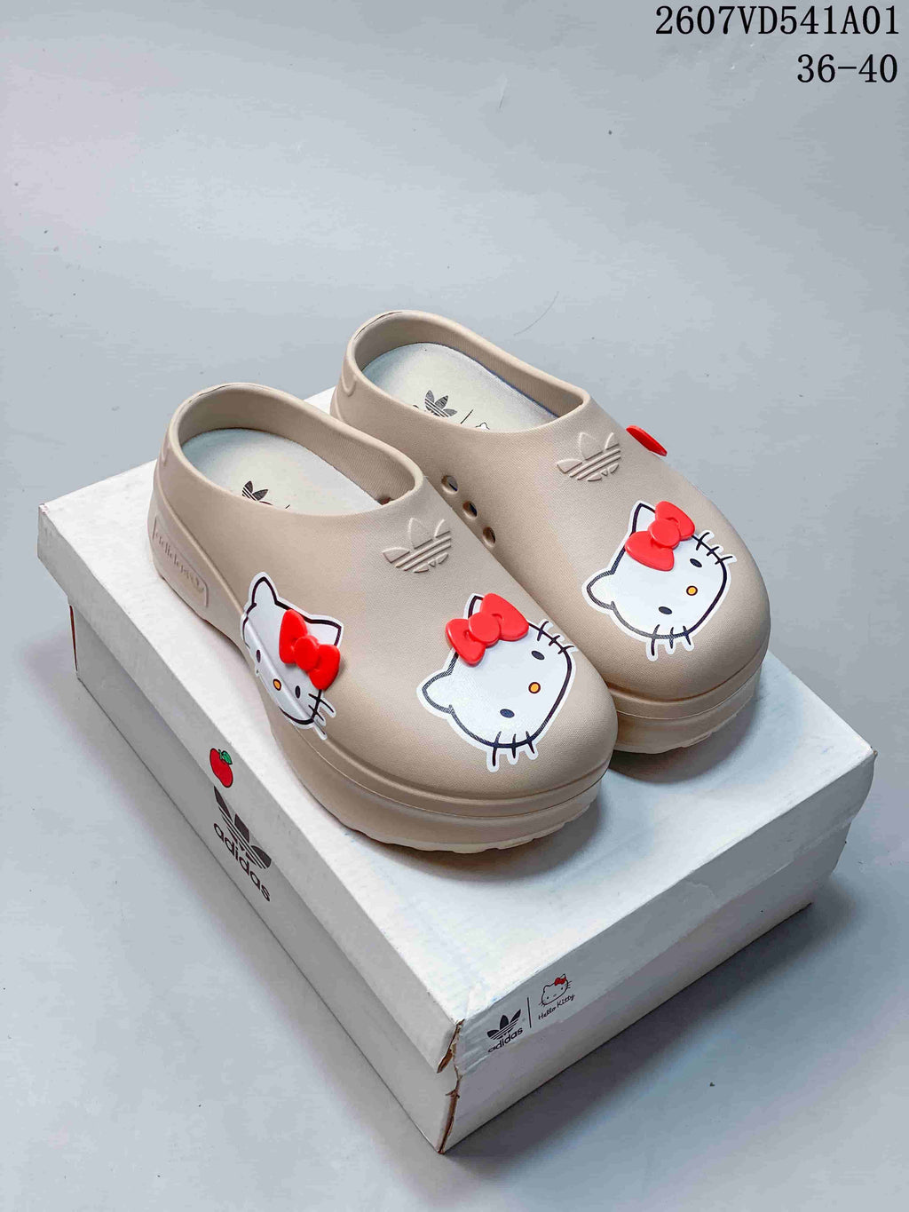 Pair of beige Hello Kitty platform mule clogs with red bow details.