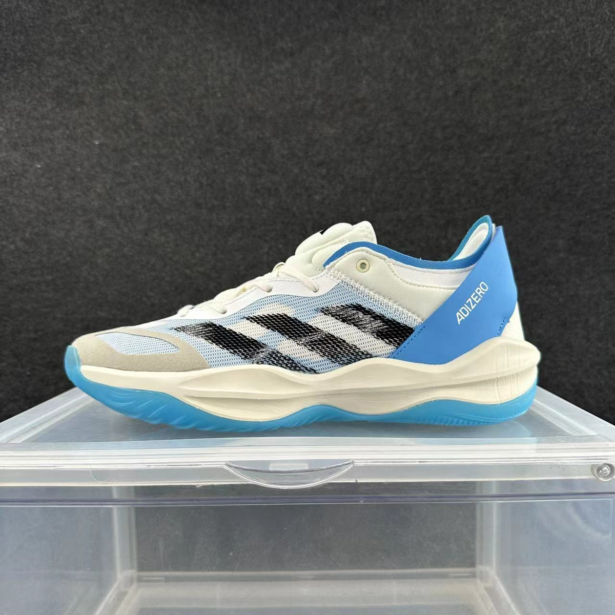 Side view of a white and light gray adidas Adizero sneaker with black stripes, blue heel detail, and blue outsole.