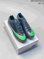 Pair of black and green Nike Mercurial soccer cleats displayed on a shoe box, with the outsole and studs partly visible.