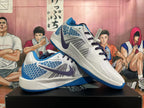 Side view of white and blue Nike basketball shoes with dark swooshes, patterned panels, and blue outsoles.