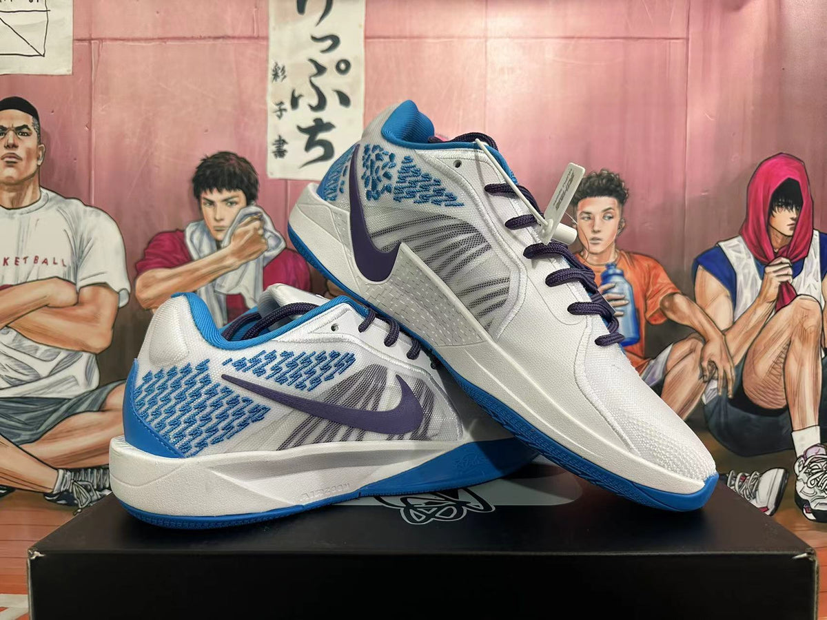 Side view of white and blue Nike basketball shoes with dark swooshes, patterned panels, and blue outsoles.