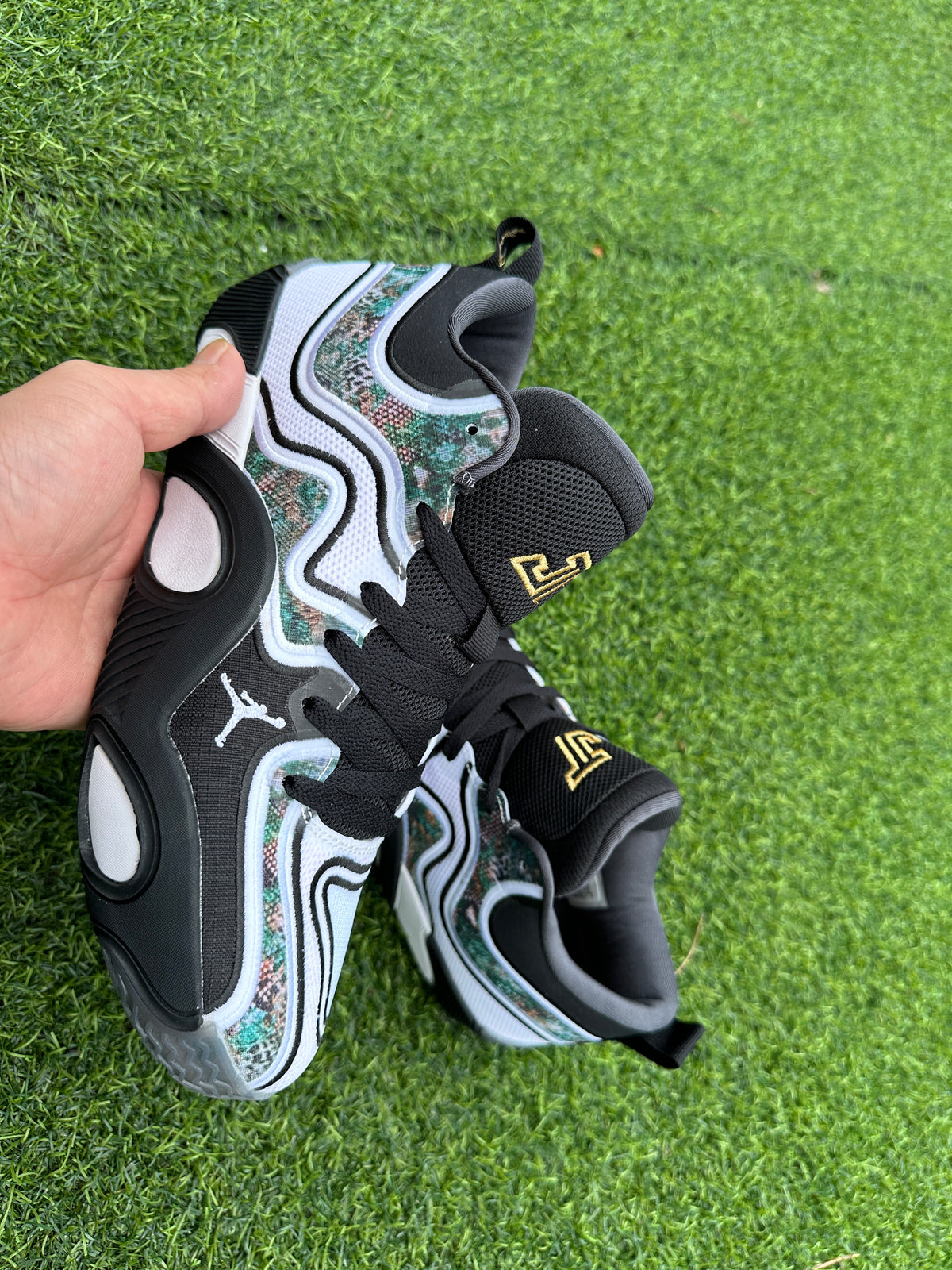 Pair of white, black, and multicolor-patterned Jordan basketball shoes on grass
