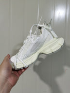 Side view of a white layered mesh sneaker showing its tonal overlays and segmented outsole.