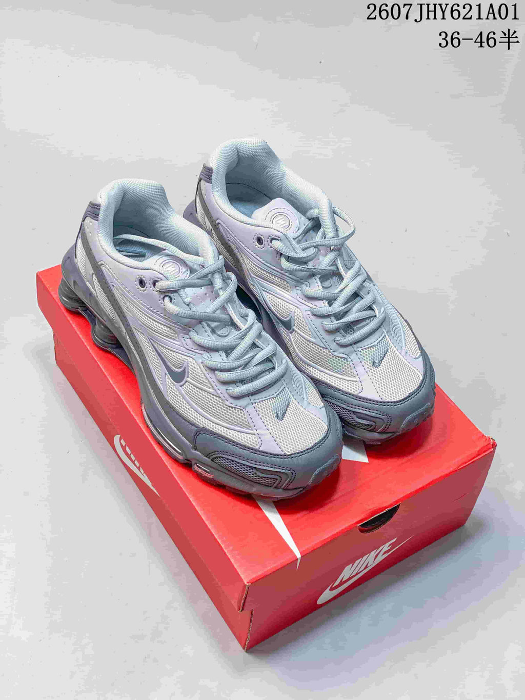 Pair of silver and gray Nike Shox Ride 2 sneakers on a red shoe box
