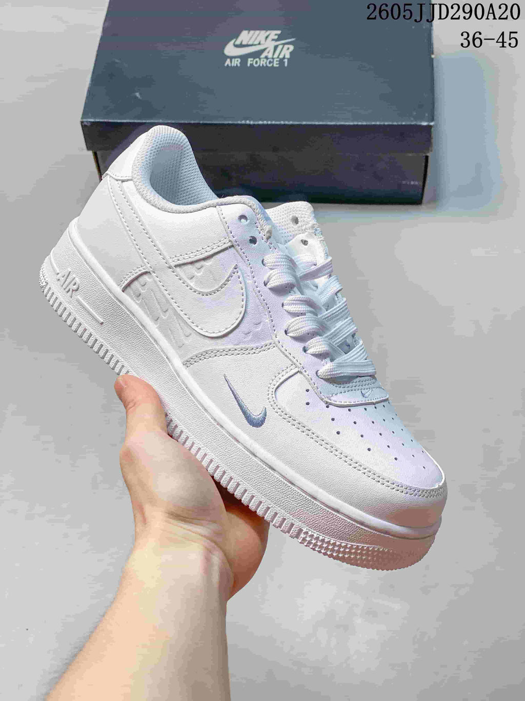 Close-up of a white Nike Air Force 1-style sneaker with tonal embossed side details and pale blue-gray accents.