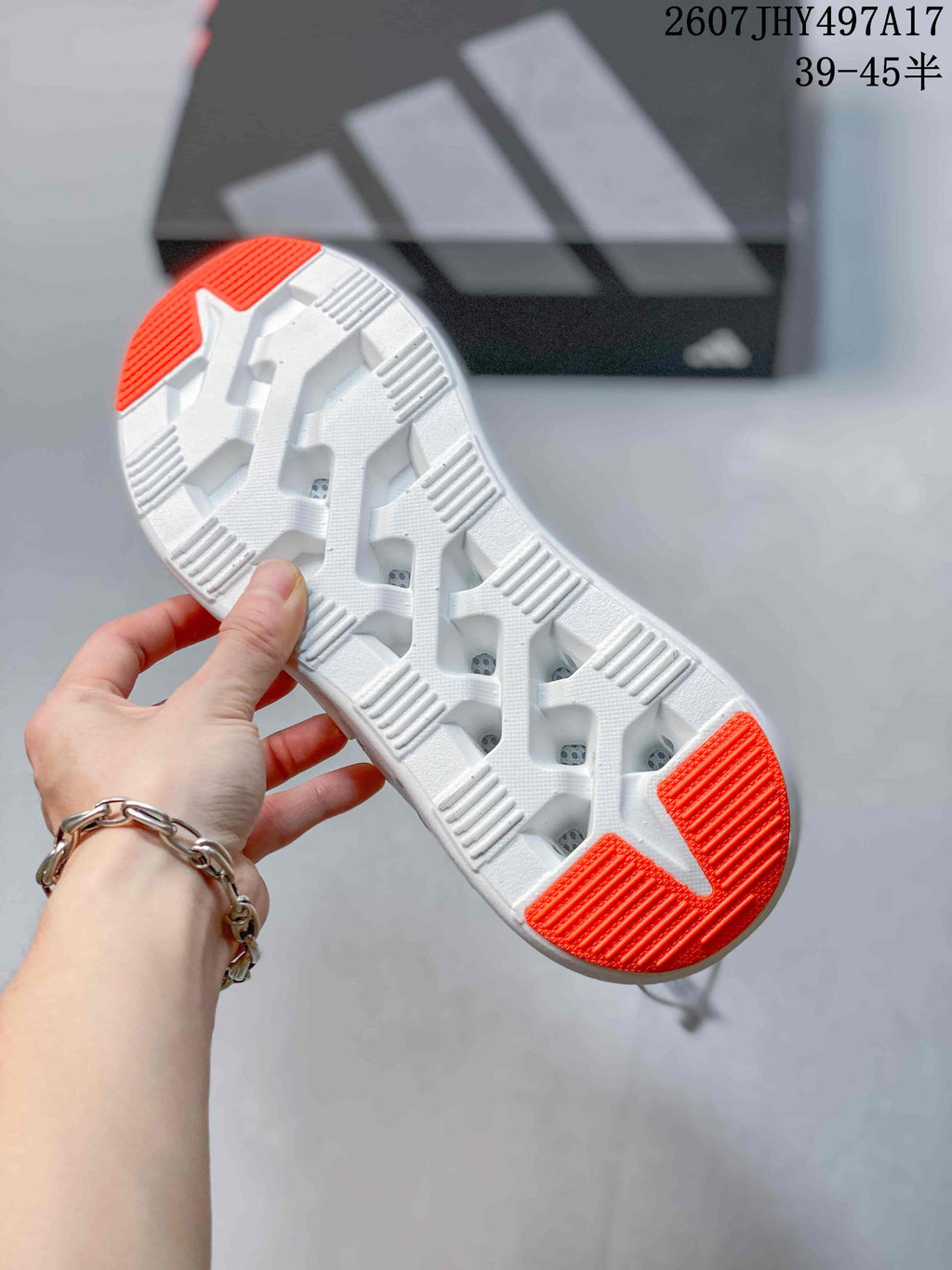 Close-up of the white outsole with orange traction sections and segmented tread geometry.