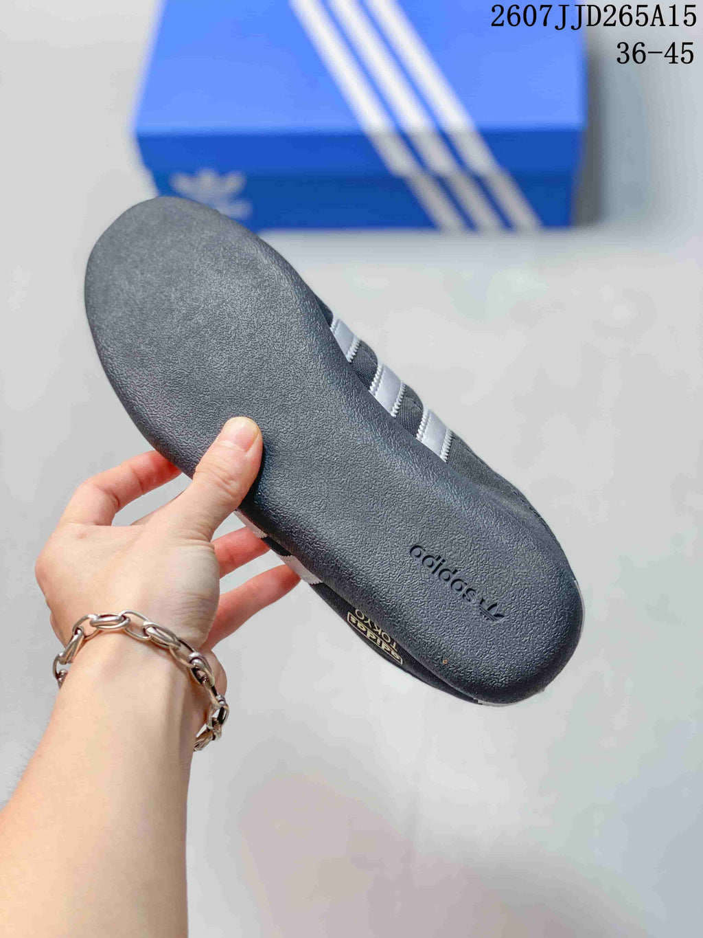 Close-up of the textured dark gray rubber outsole with adidas branding, with the blue shoebox in the background.