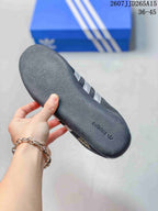 Close-up of the textured dark gray rubber outsole with adidas branding, with the blue shoebox in the background.