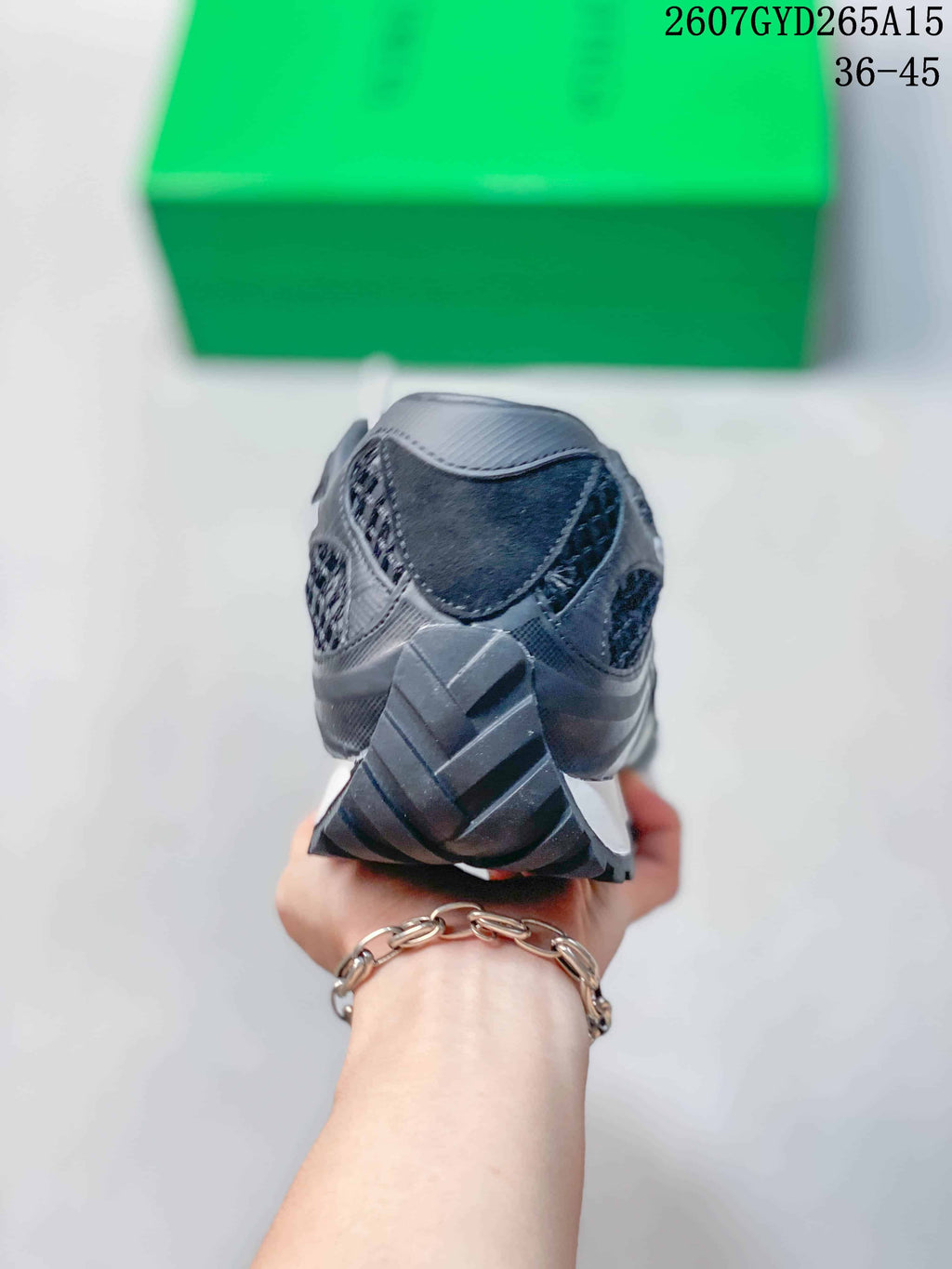Rear view of the black sneaker showing the heel structure, layered panels, and outsole tread.