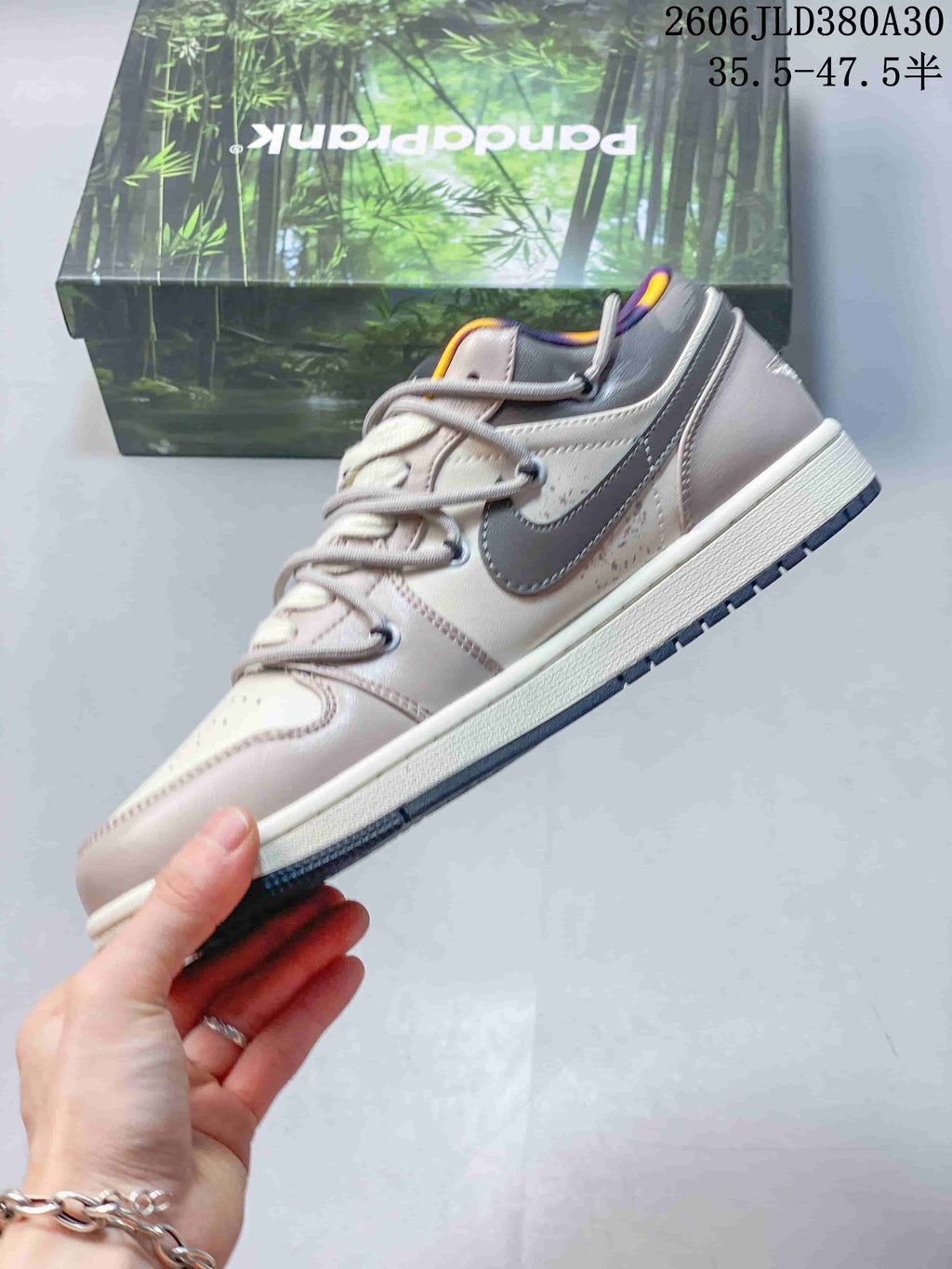 Side view of a pink and gray low-top sneaker with a gray side logo and layered laces.
