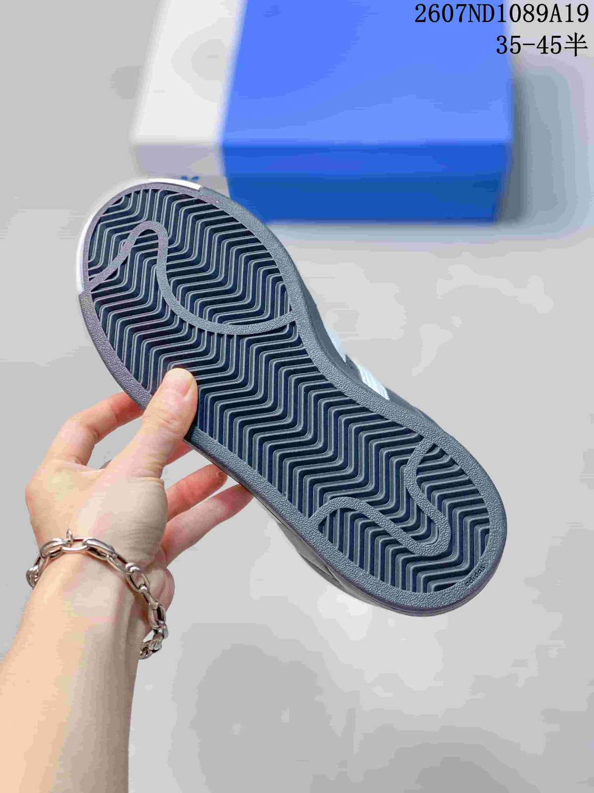 Close view of the sneaker outsole showing a dark zigzag tread pattern and curved groove details.