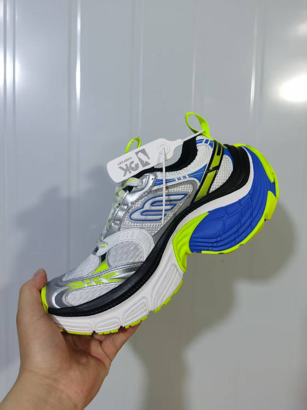 Angled view of white, blue, black, silver, and neon green chunky sneakers.