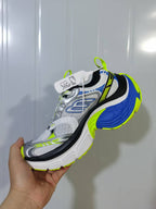 Angled view of white, blue, black, silver, and neon green chunky sneakers.