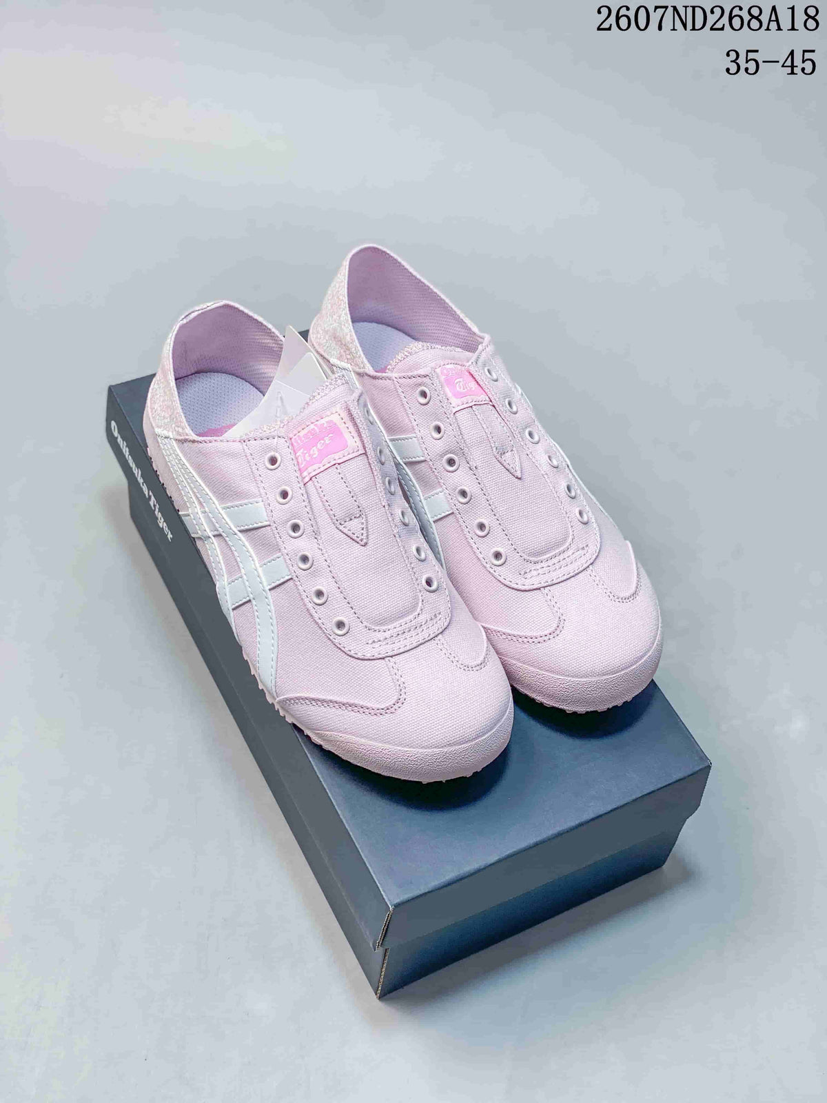 Pair of soft pink Onitsuka Tiger Mexico 66 Paraty sneakers displayed on a shoebox, showing the low-top silhouette and light-colored side stripes.