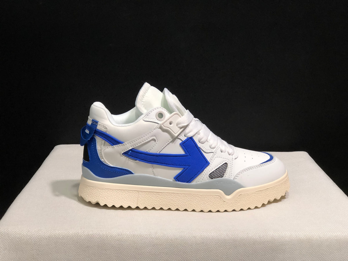 Outer side profile showing the white upper, royal blue side arrow and heel accents, and textured cream-colored sole.