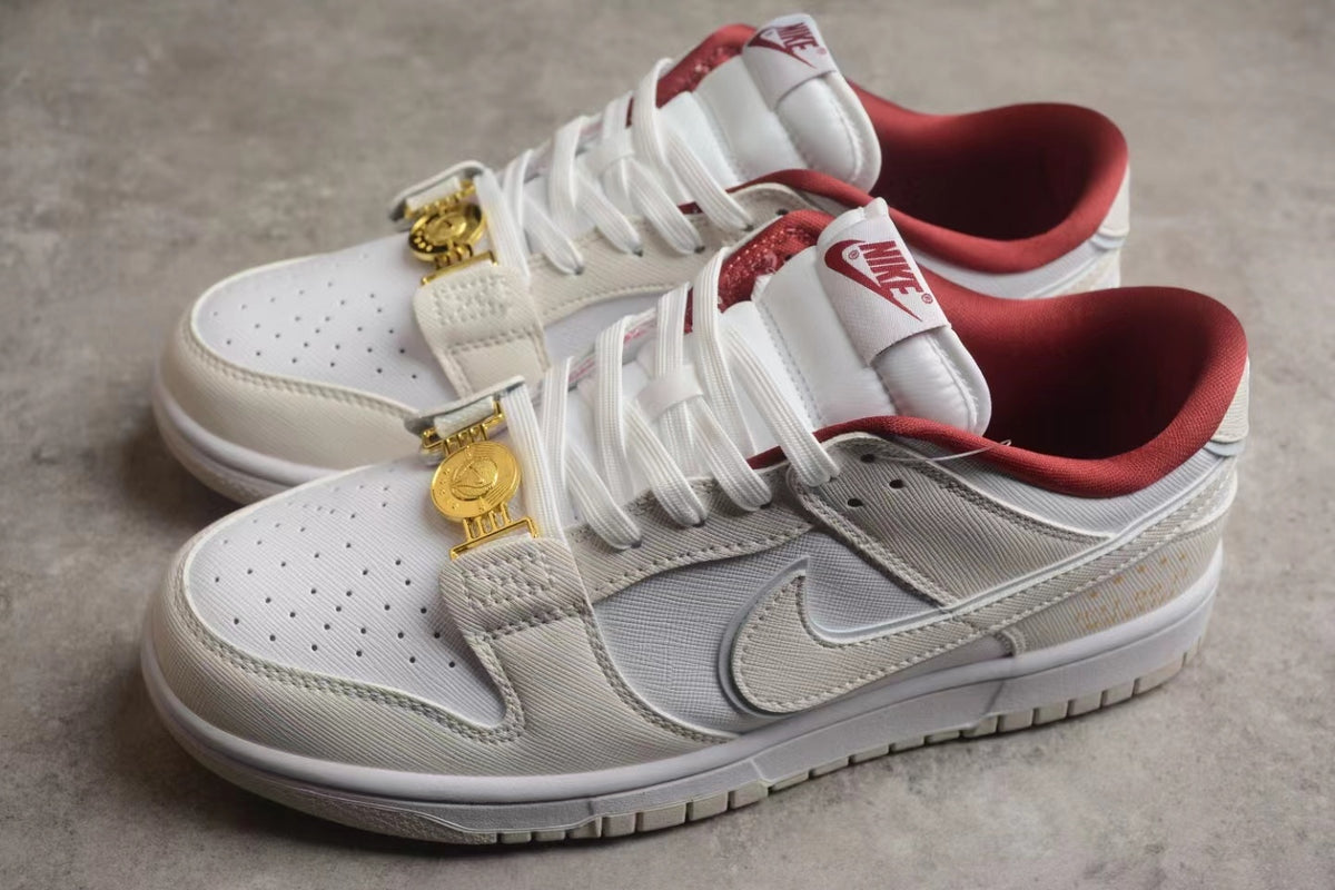 Three-quarter view of the pair showing the off-white and white upper, red collar lining, and gold-tone lace clasps.