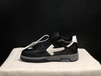 Lateral profile of a black low-top sneaker showing the white arrow detail, white heel accent, and gray outsole section.