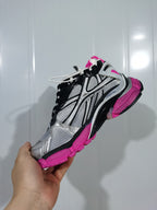 Side view showing the layered silver and black upper, mesh-textured panels, black laces, and fluorescent pink outsole.