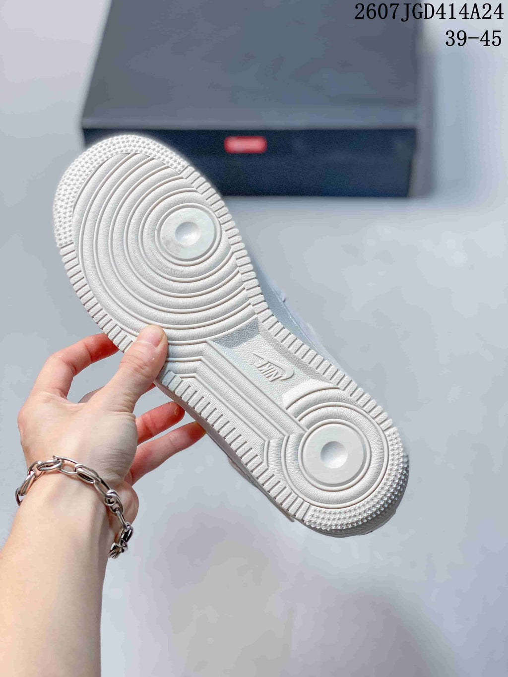 Close-up of the textured outsole on a white sneaker, showing circular tread sections and molded branding details.