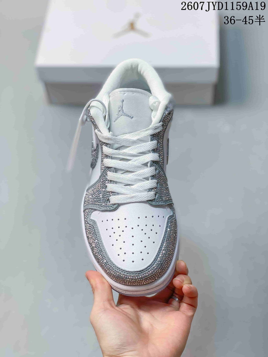 Top-down view of the sneaker showing white laces, a perforated white toe box, and silver decorative edging.