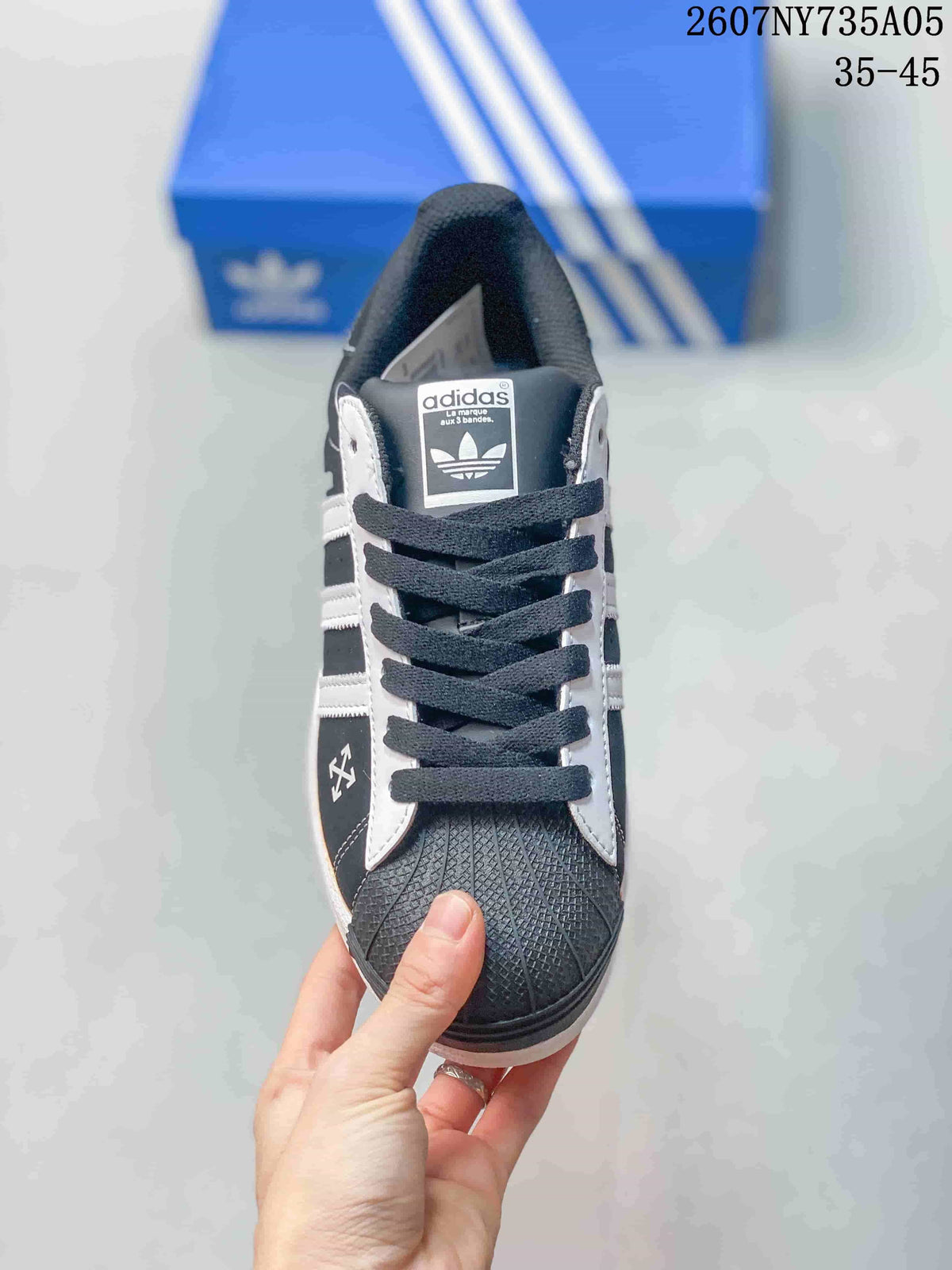 Top view showing the black laces, white eyelet panels, trefoil tongue label, and textured toe.