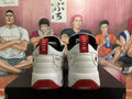 Rear view of white Jordan sneakers with red heel pull tabs, black collars, and red outsole details.