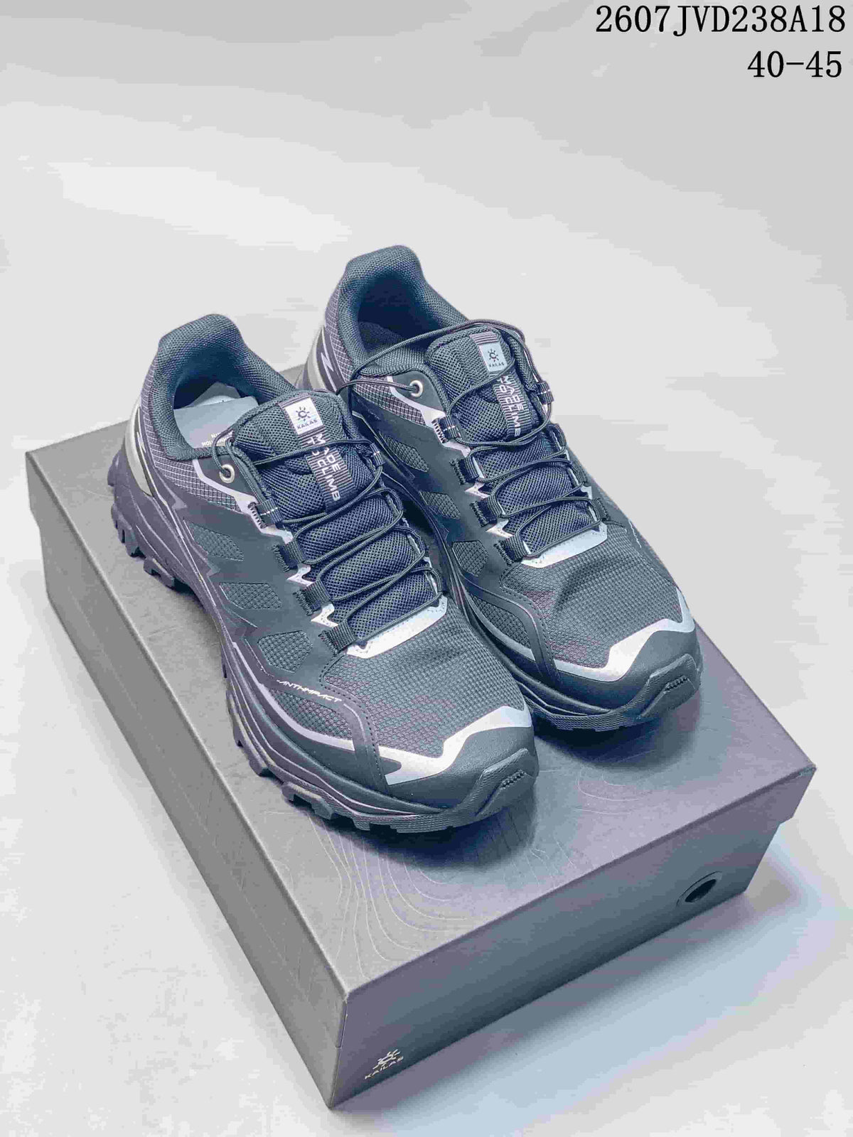 Pair of dark charcoal KAILAS low-top hiking shoes displayed on a shoebox, with lace-up panels and rugged tread visible.