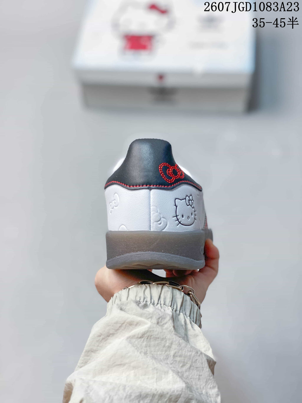 Rear view of the white sneaker showing Hello Kitty artwork, a dark heel panel, and red stitching.