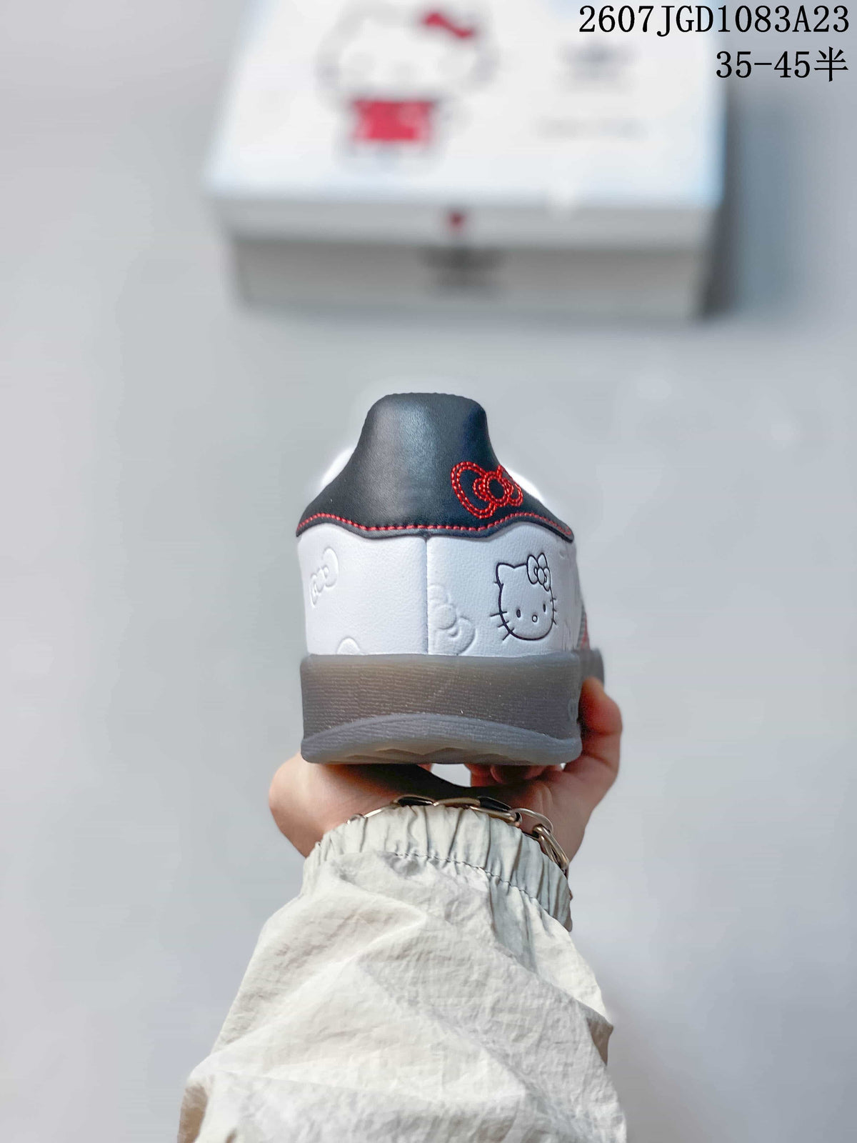 Rear view of the white sneaker showing Hello Kitty artwork, a dark heel panel, and red stitching.