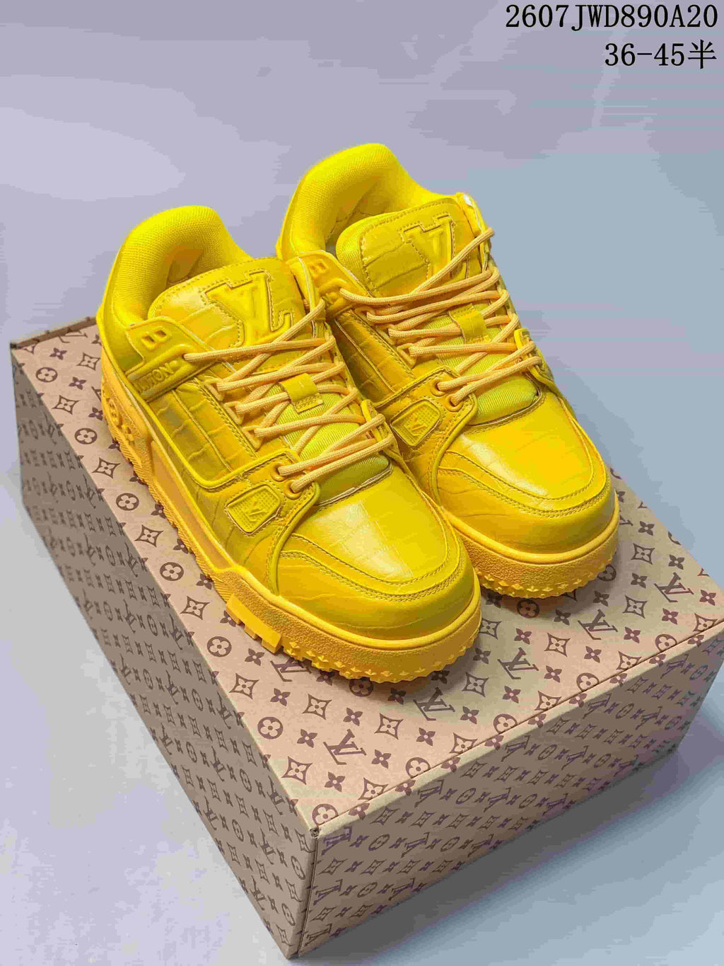 Pair of yellow Louis Vuitton Trainer Maxi sneakers displayed on a patterned shoe box, with the style code and size range visible above.