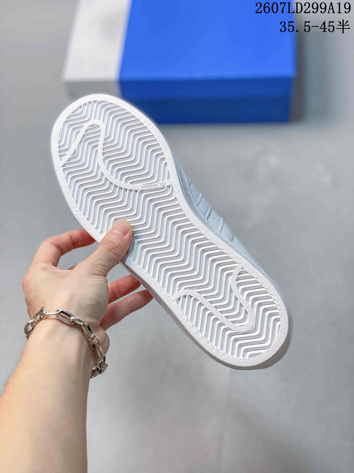Underside view of a white sneaker showing the textured herringbone outsole pattern.