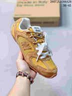 Angled view of the mustard and tan lace-up sneaker showing the rounded toe, layered upper and side logo.
